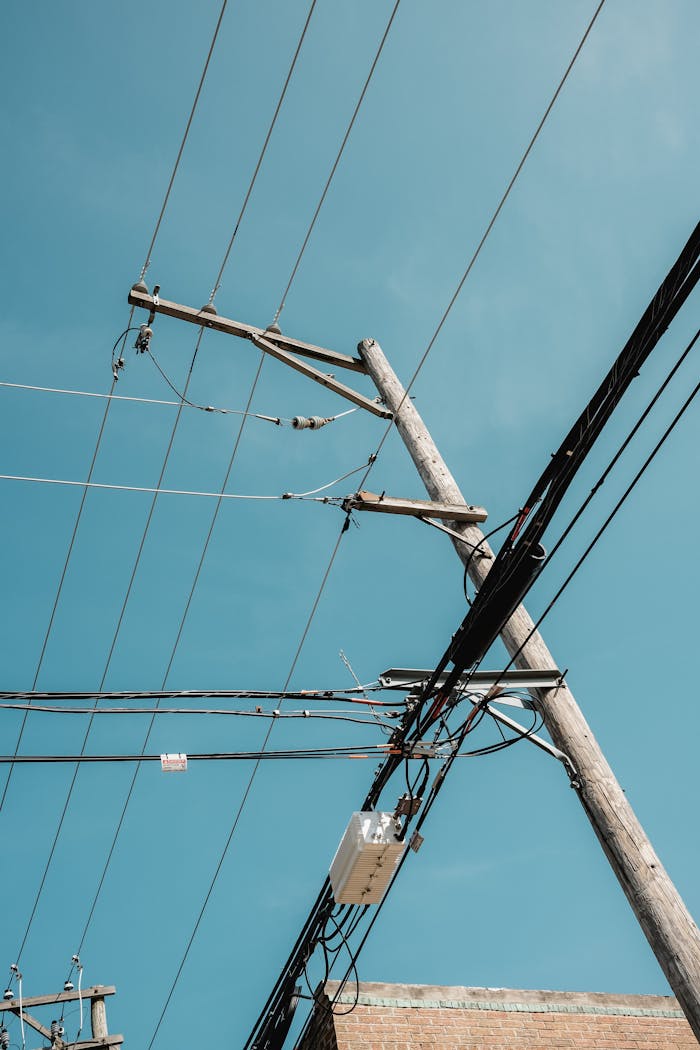 Power lines stretch across wooden poles, set against a clear blue sky.